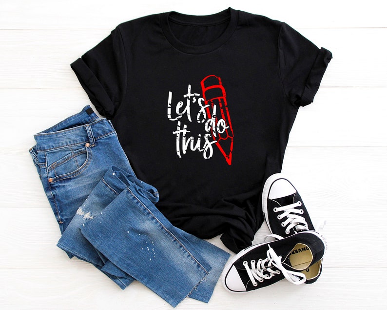 K&ouml;nnte beinhalten: Schwarzes T-Shirt mit dem wei&szlig;en Text "Let's do this" und einer roten Bleistiftgrafik. Das Shirt wird mit blauen Jeans und schwarzen Canvas-Sneakern mit wei&szlig;en Sohlen und Schn&uuml;rsenkeln kombiniert.