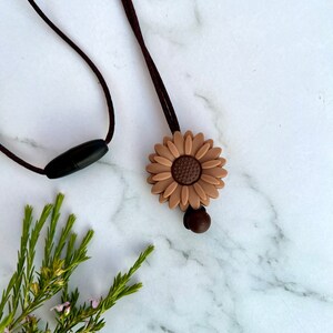 May include: A brown silicone sunflower charm necklace with a brown cord and a black plastic clasp.
