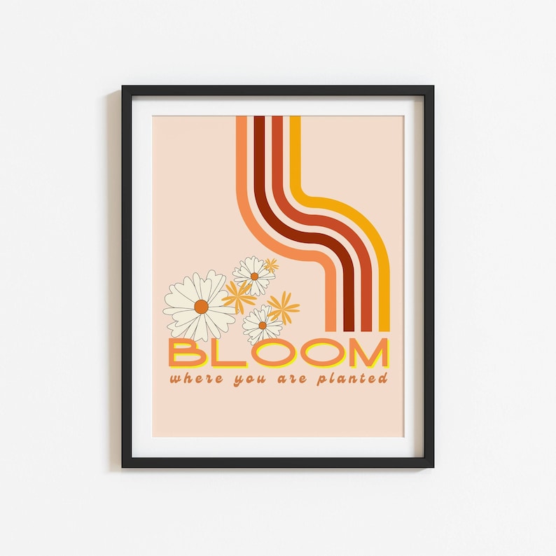 May include: A peach-coloured poster with a retro design featuring a curved line of orange, red and brown stripes. The poster has a white daisy flower design and the text "BLOOM where you are planted".