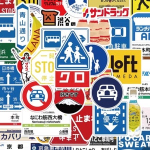 May include: A collection of colorful Japanese stickers featuring various designs, including traffic signs, logos, and illustrations. The stickers feature Japanese text, such as "Stop", "Crosswalk", "Loft", and "Nihonbashi".