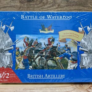May include: A blue box set titled "Battle of Waterloo" featuring a historical diorama of British artillery. The set includes 36 pieces, two cannons, and crews. The scale is 1/72, with figures at 25mm.