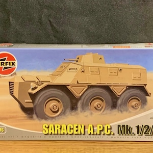 Puede incluir: Caja de maqueta que representa un vehículo blindado de transporte de personal Saracen A.P.C. Mk. 1/2/3 de color beige. La caja tiene el logotipo de Airfix y la escala 1:76. La ilustración muestra el vehículo en un entorno desértico.