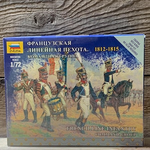 May include: A box featuring a painted illustration of French Line Infantry soldiers from 1812-1815. The box includes the text "French Line Infantry Command Group" and "Scale 1/72". The box is on a wooden surface.