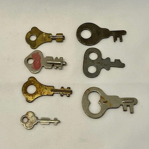 May include: Eight antique keys of different designs and sizes. The keys are made of metal, showing signs of age, with colours from gold to silver and dark brown. Some keys have circular or oval keyholes, and are of various lengths.