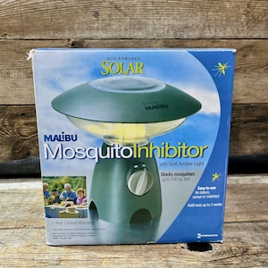 May include: A green Malibu Mosquito Inhibitor with a solar panel. The product has a soft amber light and blocks mosquitoes up to 100 sq. feet. The box also includes the text "Easy to use" and "Refill lasts up to 3 weeks."