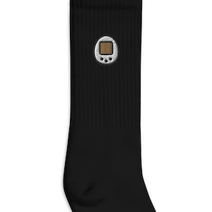 Könnte beinhalten: Schwarze Socken mit einem gestickten Bild einer tragbaren Videospielkonsole in Weiß und Braun.