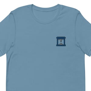 May include: A light blue t-shirt with a small, embroidered image of a 3D printer on the left chest.