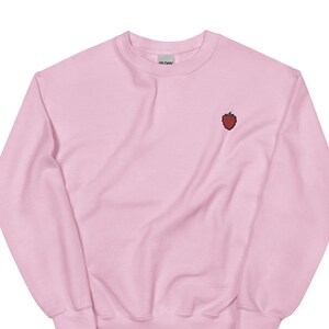 May include: A pink sweatshirt with a small embroidered strawberry on the front.