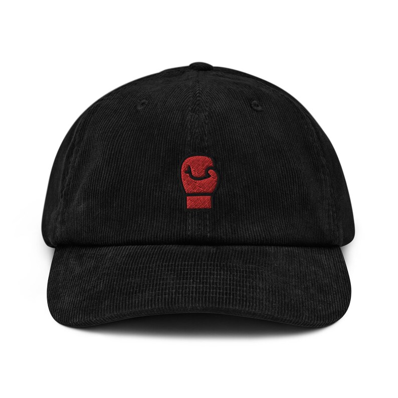 May include: A black corduroy baseball cap with a red embroidered boxing glove on the front.
