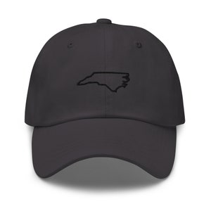 K&ouml;nnte beinhalten: Eine dunkelgraue Baseballkappe mit einer gestickten Umrandung des Bundesstaates North Carolina in Schwarz.