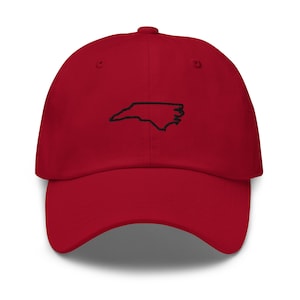 K&ouml;nnte beinhalten: Rote Baseballkappe mit einem schwarzen gestickten Umriss des Bundesstaates North Carolina.