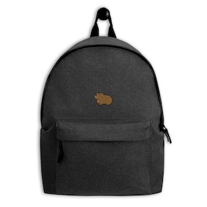 May include: A dark gray backpack with a front pocket and a small brown capybara patch. The backpack has a top handle and black zippers. The capybara is embroidered on the front of the backpack.