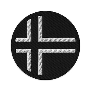May include: A black circular patch with a white cross design. The cross is formed by four lines that meet in the centre of the circle.