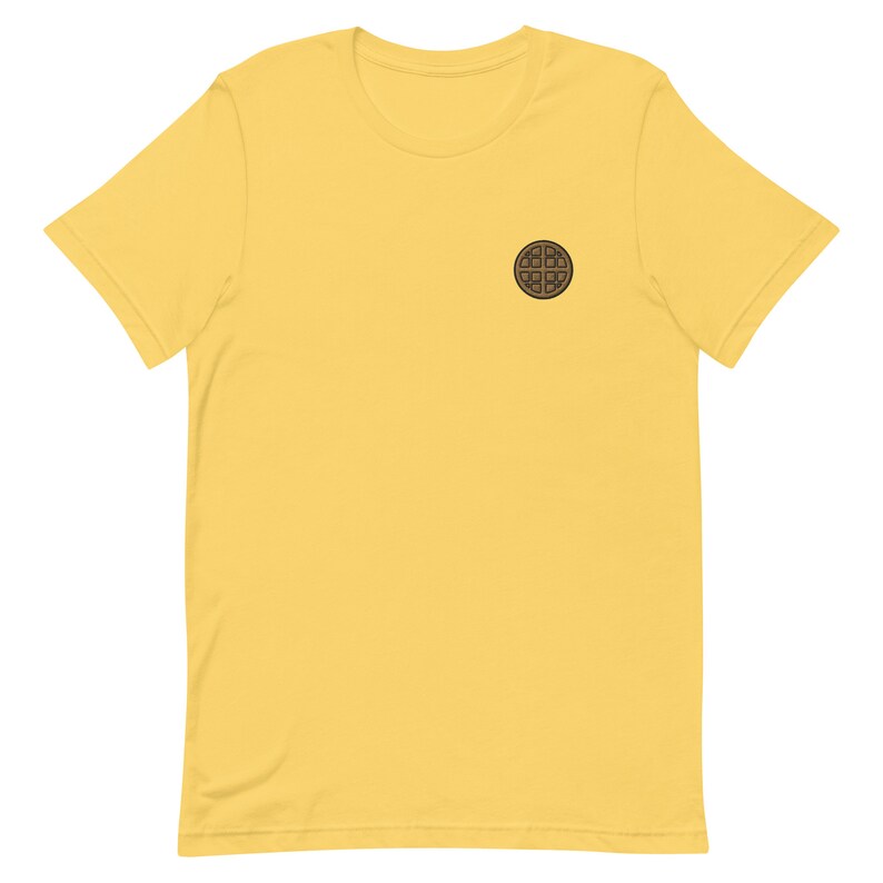 Op de afbeelding: Een geel T-shirt met korte mouwen met een klein bruin wafelmotief op de voorkant.