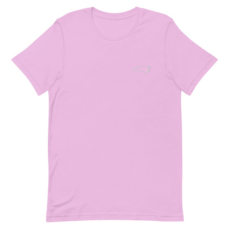 Puede incluir: Una camiseta rosa claro con un contorno blanco del estado de Carolina del Norte en la parte delantera.