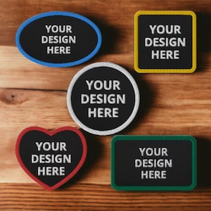 Puede incluir: Cinco parches bordados con diferentes formas y colores. Cada parche tiene el texto "YOUR DESIGN HERE" en bordado blanco.