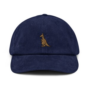 May include: A navy blue corduroy baseball cap with an embroidered brown kangaroo on the front.