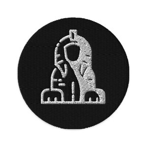 May include: A black and white embroidered patch featuring a stylised image of a sphinx. The patch is circular and has a white outline.