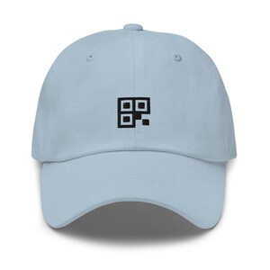 Könnte beinhalten: Eine hellblaue Baseballkappe mit einem schwarzen gestickten Design eines Quadrats mit kleineren Quadraten darin.