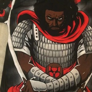 Puede incluir: Una camiseta negra y roja con un estampado gr&aacute;fico de un guerrero samur&aacute;i negro que lleva una capa roja y sostiene dos espadas. El guerrero tiene un afro negro y una expresi&oacute;n seria.
