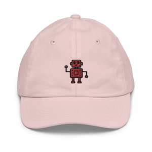 May include: A pink baseball cap with an embroidered red robot design. The robot has a square head with two eyes and a mouth, and two arms and legs.