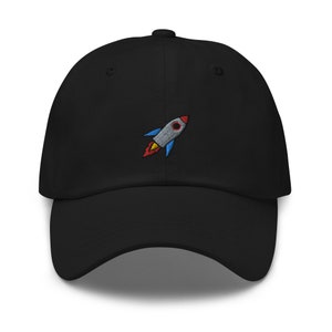 May include: A black baseball cap with an embroidered rocket ship design in red, blue, and yellow.
