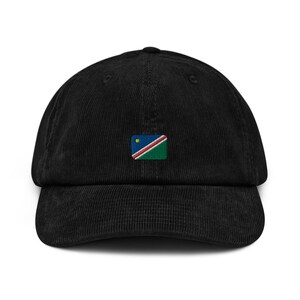 Op de afbeelding: Een zwarte corduroy baseballpet met een geborduurde vlag van Namibië op de voorkant.