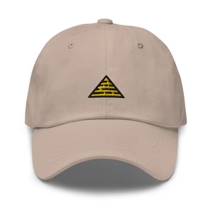 May include: A beige baseball cap with a black and yellow embroidered triangle design.