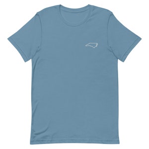 Puede incluir: Una camiseta azul claro con un contorno blanco del estado de Carolina del Norte en la parte delantera.