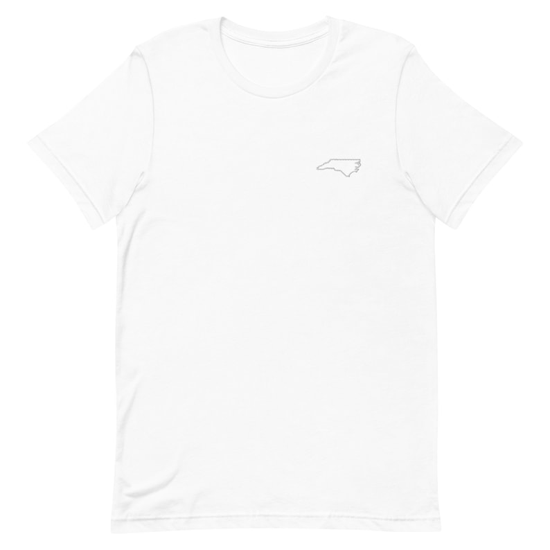 Puede incluir: Camiseta blanca con un peque&ntilde;o contorno del estado de Carolina del Norte en el pecho izquierdo.