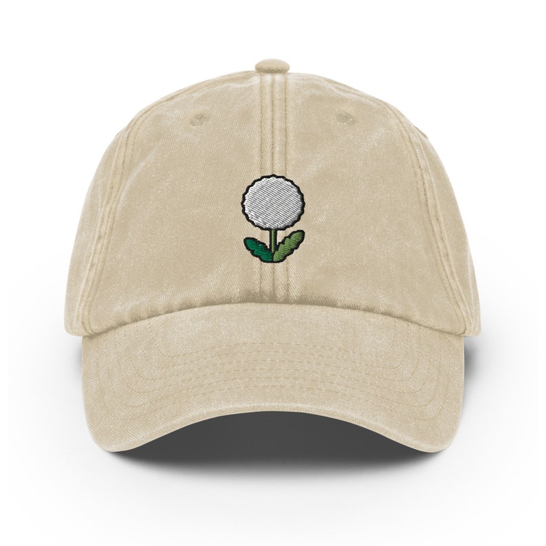 May include: A beige cotton baseball cap with an embroidered white dandelion design.