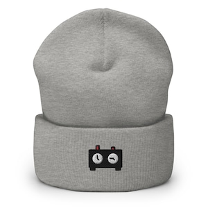 May include: Gray beanie with a black and white embroidered image of a clock with red knobs.