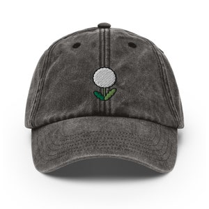 May include: A black vintage washed cotton baseball cap with an embroidered white dandelion design.