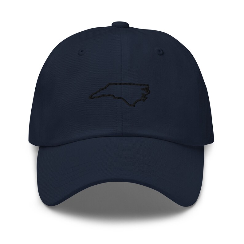 K&ouml;nnte beinhalten: Eine marineblaue Baseballkappe mit einer gestickten Umrandung des Bundesstaates North Carolina in Schwarz.