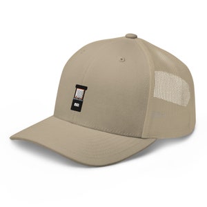 May include: A beige and brown trucker hat with a black and white embroidered image of a retro arcade game.