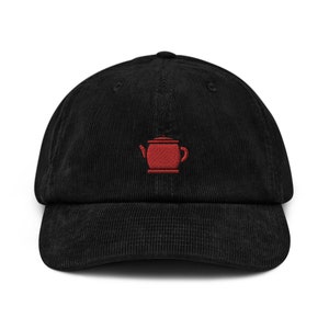 May include: A black corduroy baseball cap with a red embroidered teapot design.