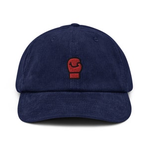 May include: A navy blue corduroy baseball cap with a red embroidered boxing glove on the front.