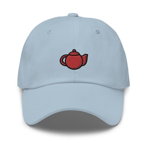 Puede incluir: Una gorra de béisbol azul claro con un diseño de tetera roja bordada.
