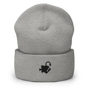 Puede incluir: Gorro gris con un gráfico de pez pescador negro bordado en la parte delantera.