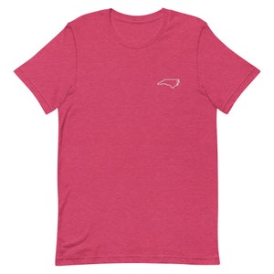 Puede incluir: Una camiseta rosa de manga corta con un contorno blanco del estado de Carolina del Norte en la parte delantera.