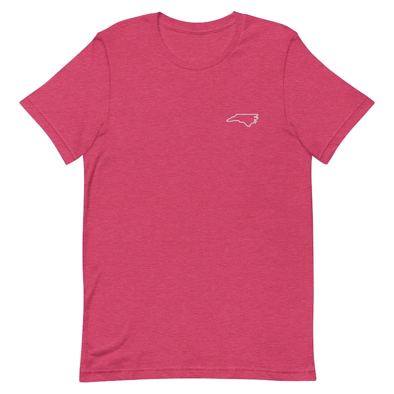 Puede incluir: Una camiseta rosa de manga corta con un contorno blanco del estado de Carolina del Norte en la parte delantera.