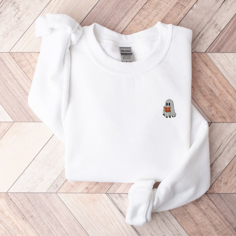 May include: White sweatshirt with a small embroidered design of a ghost reading a book.