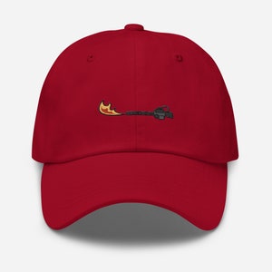 May include: A red baseball cap with an embroidered design of a flame thrower. The flame is yellow and orange, and the flamethrower is black and gray. The cap is made of a soft material and has a curved brim.