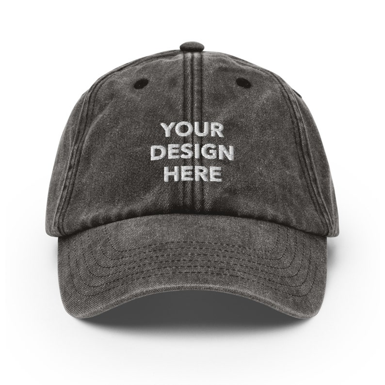 May include: A black distressed baseball cap with the text "YOUR DESIGN HERE" embroidered in white on the front.