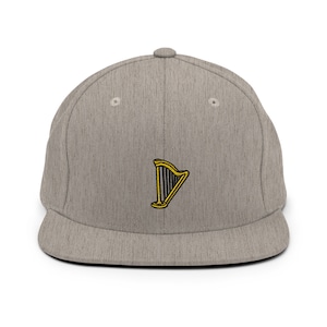 May include: A grey and black flat brimmed baseball cap with a gold and black harp embroidered on the front.