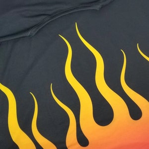 Puede incluir: Tela negra con un dise&ntilde;o de llamas amarillas y naranjas. Las llamas son estilizadas y tienen un efecto degradado.