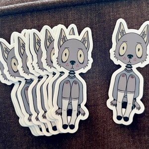 May include: A set of eight grey and white stickers featuring a cartoon wolf with large eyes and a sad expression. The wolf is wearing a grey sweater and white socks. The stickers are printed on white paper.