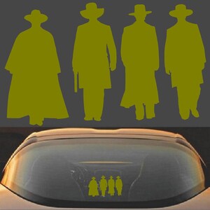 May include: A yellow silhouette of four figures in cowboy hats and long coats, reminiscent of a Western theme. The figures are standing against a gray background. A car window displays a sticker of the same figures.