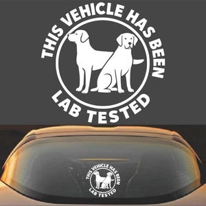 Puede incluir: Pegatina blanca con un contorno negro de dos labradores y el texto "This Vehicle Has Been Lab Tested".