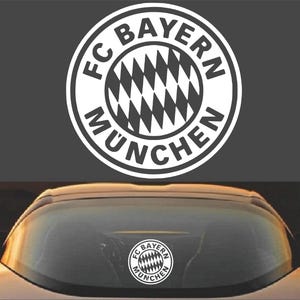 May include: A white vinyl sticker with the FC Bayern München logo. The logo is a circle with the words "FC Bayern München" around the outside and a black and white checkered pattern inside.
